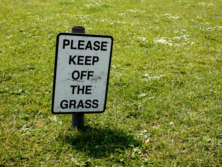 Image of a lawn with a sign that reads Please Keep Off The Grass