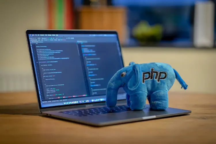 A photo of laptop with a stuffed elephant toy on the keyboard with a PHP logo on it. Photo by Ben Griffiths on Unsplash